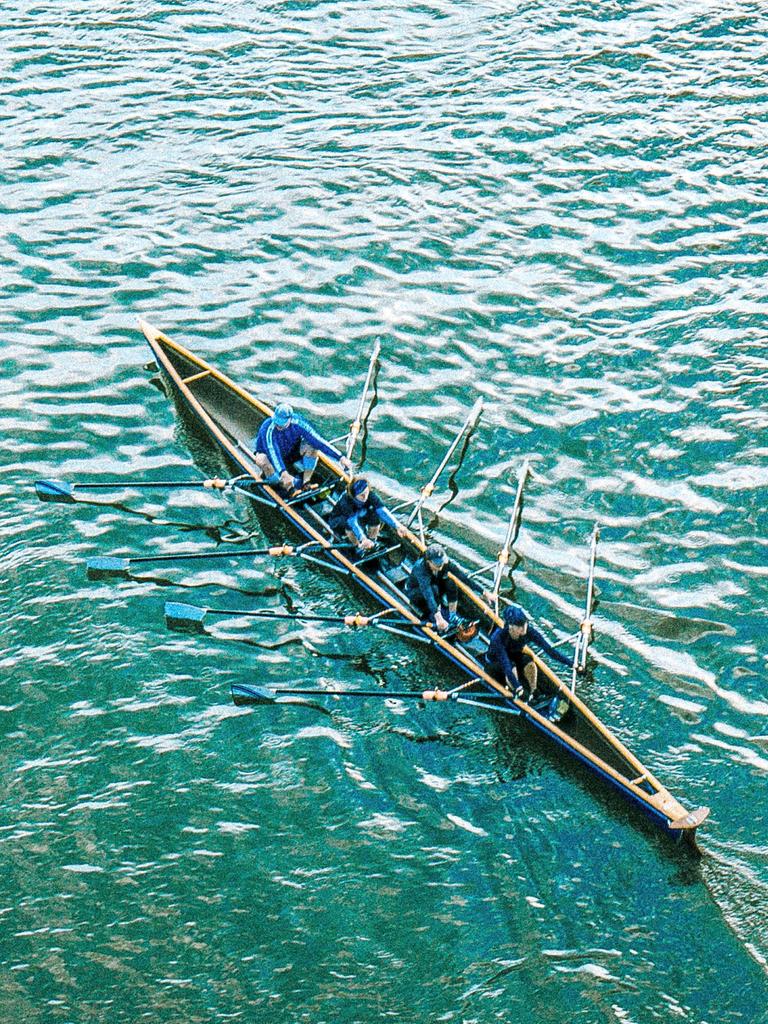 Vogelperspektive auf türkisfarbenes Wasser: Darauf ein Ruderboot mit vier Personen.