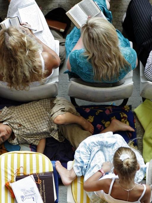 Aufnahme aus der Vogelperspektive auf die vollen Zuschauerränge in der Hamburger AOL Arena. Zwischen zwei Reihen liegt ein Kind auf einer Decke, die Arme sind hinter dem Kopf verschränkt, in Gedanken versuken.