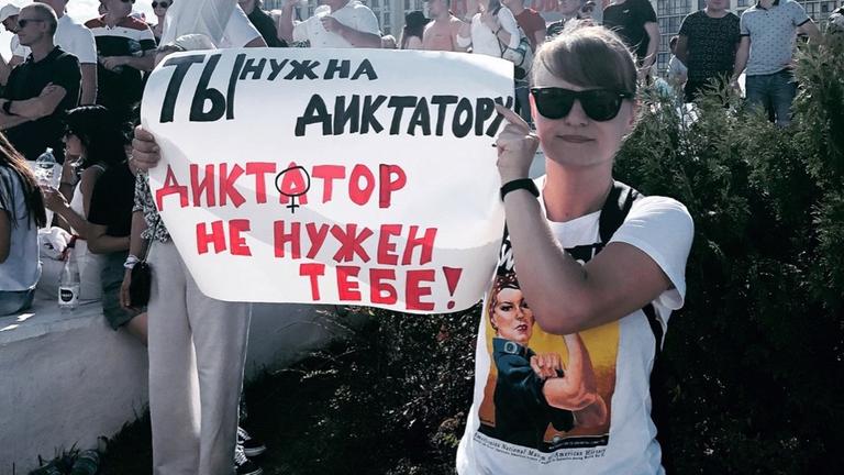 Ein Frau hält bei Demonstrationen ein Schild hoch, auf dem steht: "Der Diktator braucht dich, du brauchst keinen Diktator."