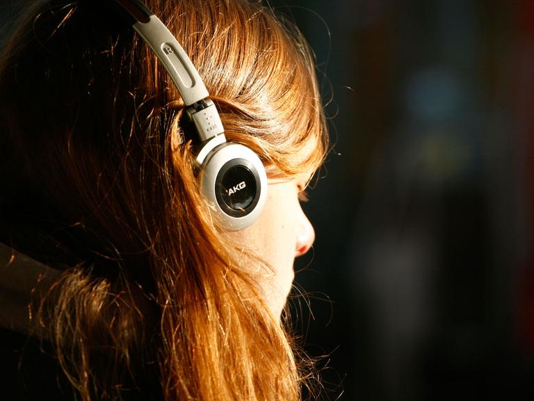 Eine junge Frau mit Kopfhörern lauscht versonnen den Tönen. 