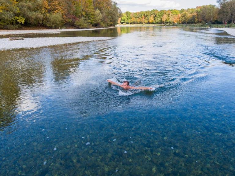 Mann schwimmt in der kalten Isar in München.