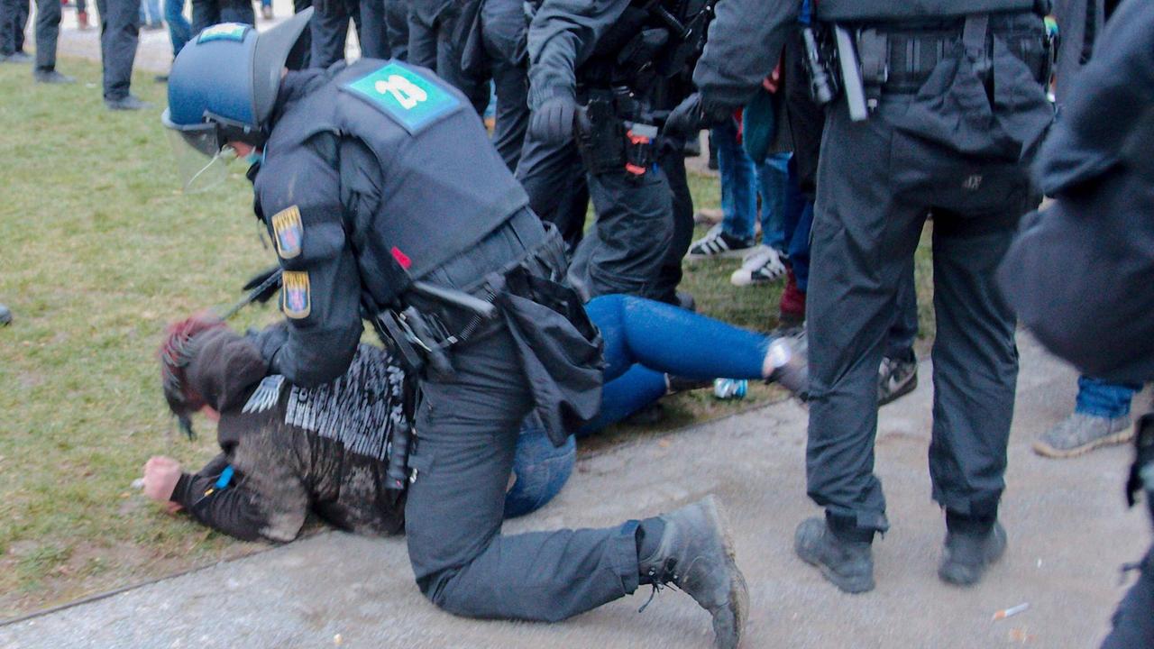 Ein Polizist hält einen Demonstranten am Boden, umgeben von weiteren Polizisten.
