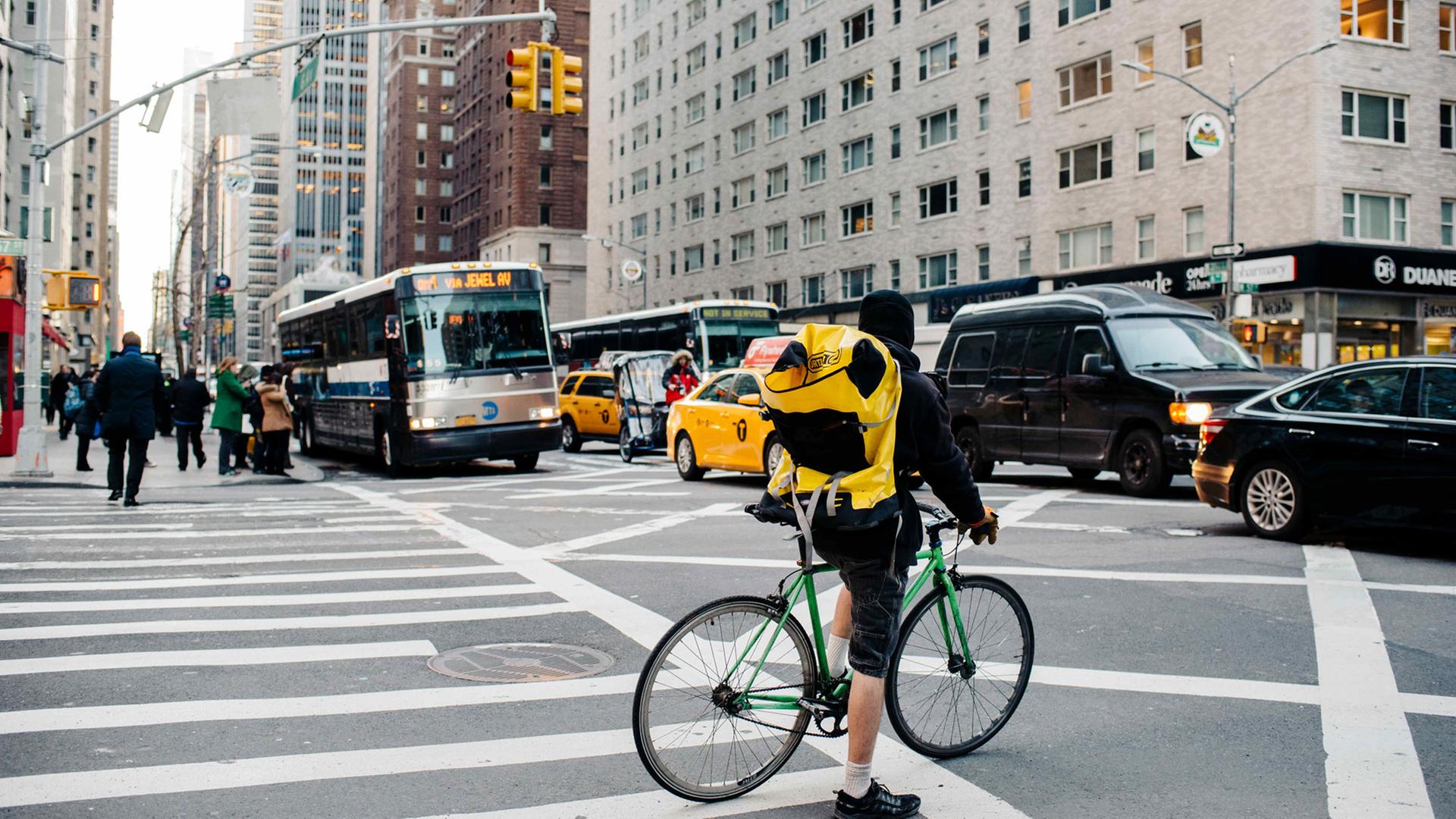 Ein Fahrradkurier wartet am 02.03.2016 an einer Ampel in Midtown Manhattan in New York (USA) auf den vorbeirollenden Verkehr