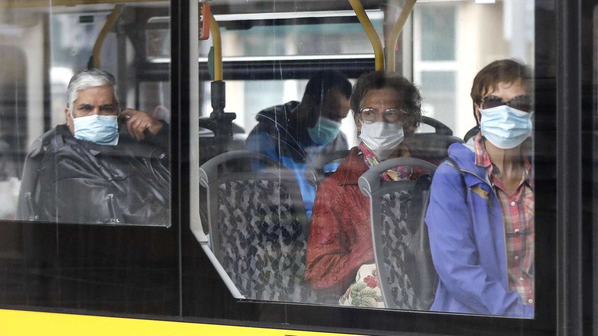 Fahrgäste mit Gesichtsmasken in einem Bus.