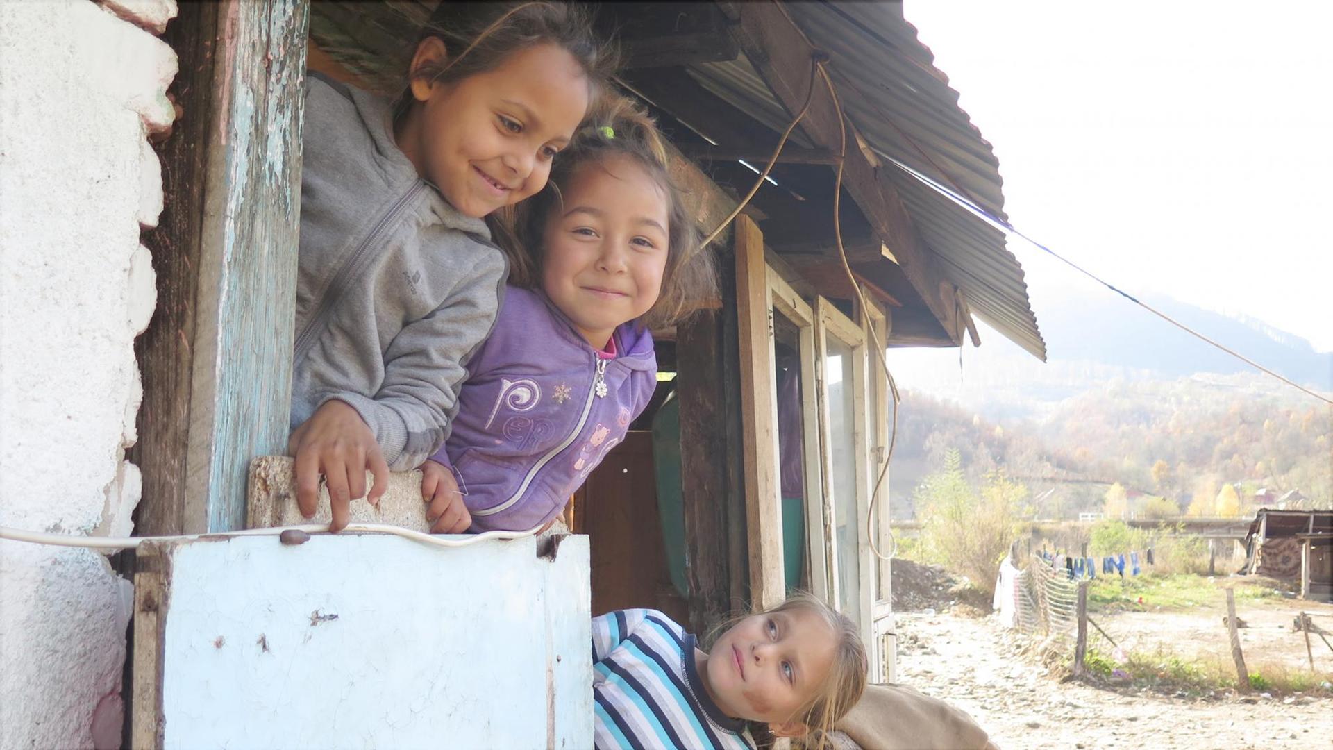 Annas Töchter spielen vor der Haustür der kleinen zusammengezimmerten Hütte. Essen gibt es selten, immerhin: Es regnet nicht mehr durch das Dach. Zlatna, Rumänien.