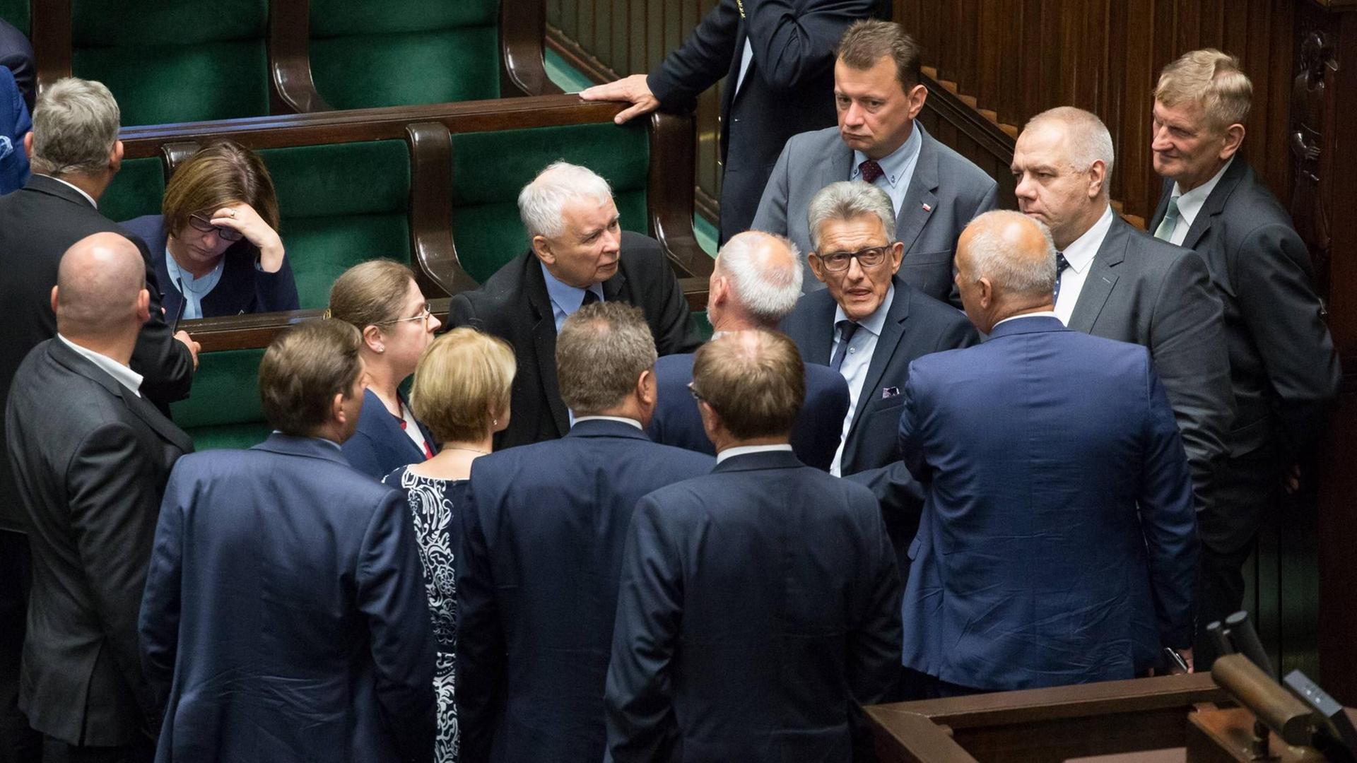 Jaroslaw Kaczynski, Chef der polnischen Regierungspartei PiS, während einer nächtlichen Debatte zur Justizreform im polnischen Parlament (Sejm), umringt von diskutierenden Abgeordneten.