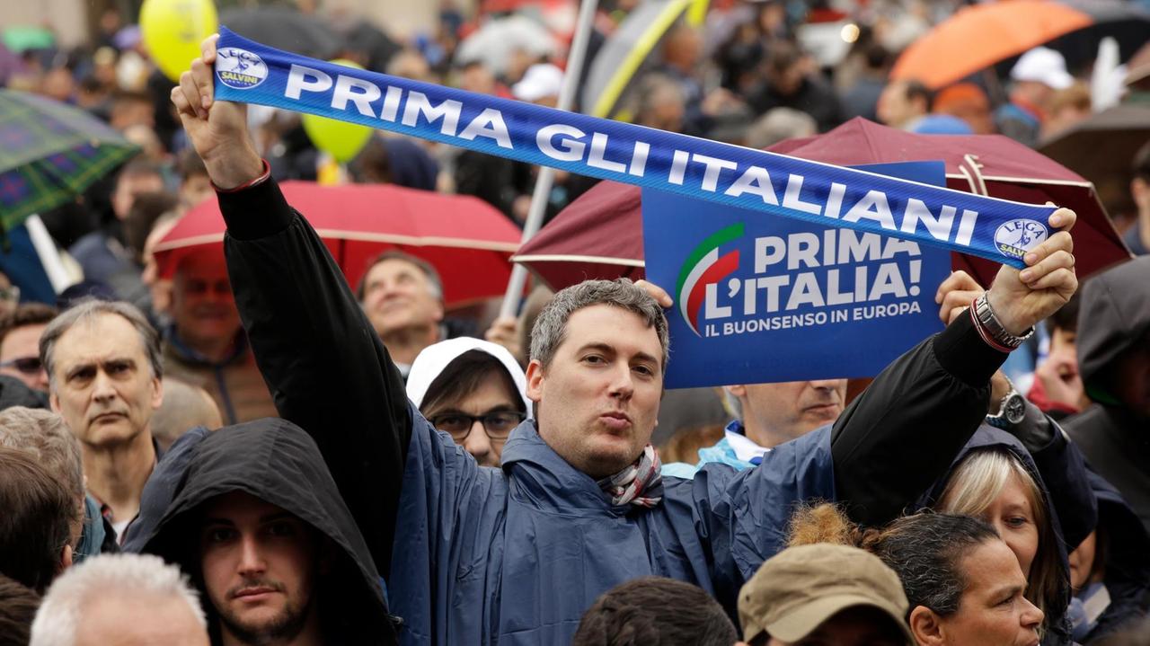 Das Foto zeigt eine Kundgebung in Mailand, ein Mann hält einen Schal mit der Aufschrift (übersetzt): "Die Italiener zuerst".