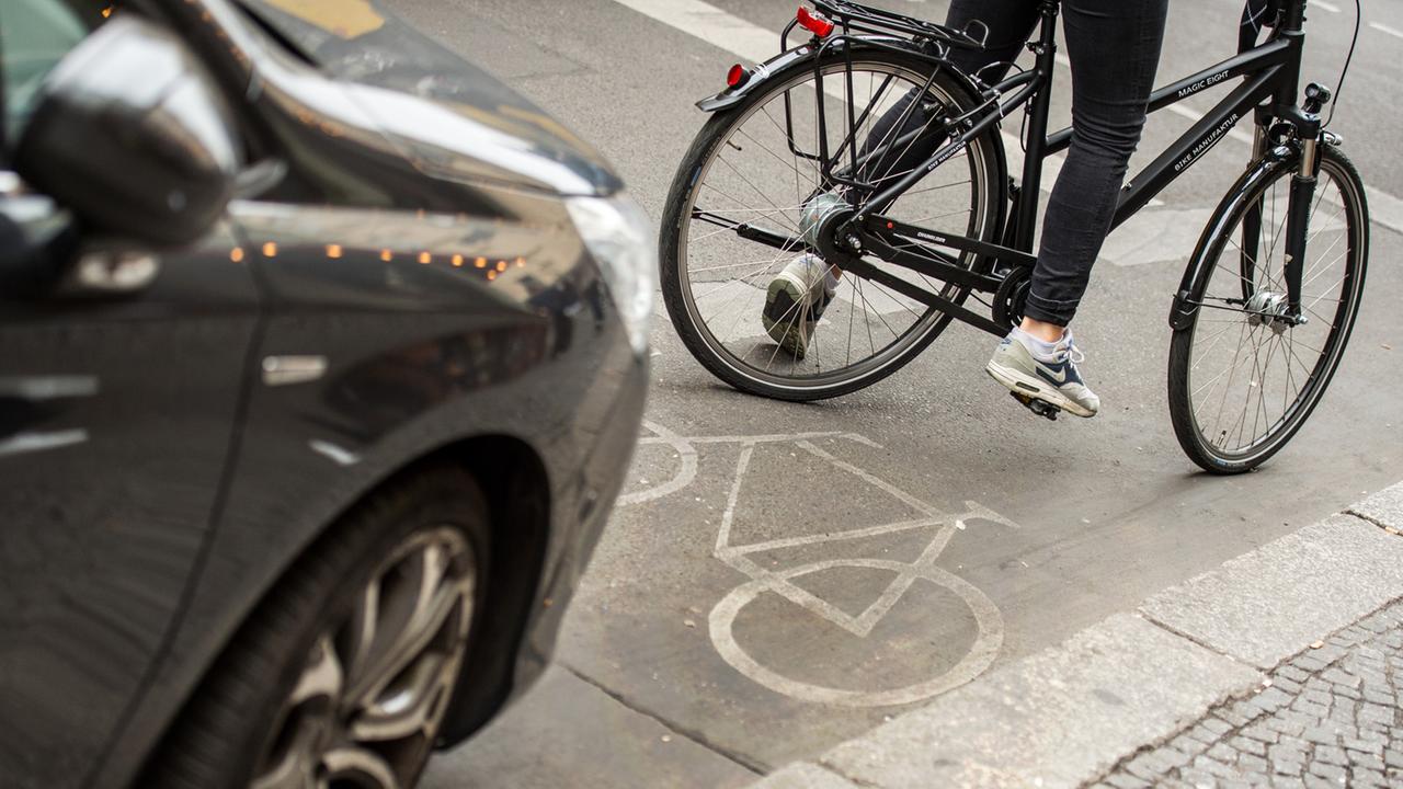 Eine Radfahrerin umfährt in Berlin ein auf dem Radweg stehendes Auto.