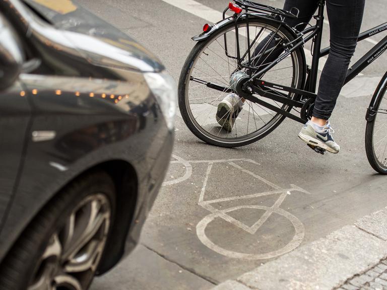 Eine Radfahrerin umfährt in Berlin ein auf dem Radweg stehendes Auto.