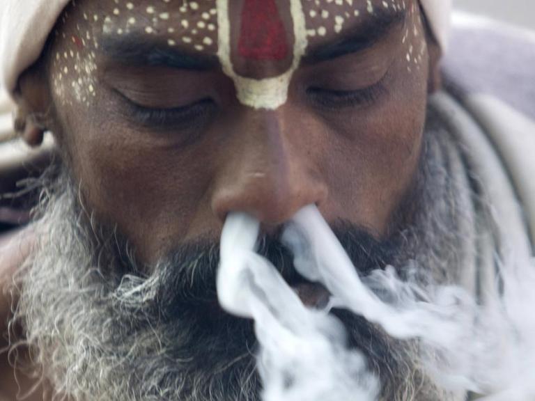 Einem Hindu Priester in Kathmandu, Nepal, strömt Rauch aus beiden Nasenlöchern. 