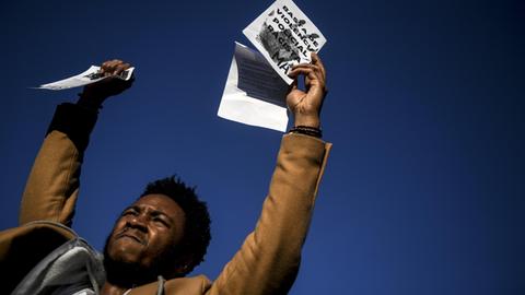 Ein Mann hält ein Papier hoch mit der Aufschrift "Genug von rassistischer Polizeigewalt" während einer Demonstration gegen Rassismus und Missbrauch von polizeilicher Gewalt in Seixal, einem Vorort von Lissabon, am 25. Januar 2019