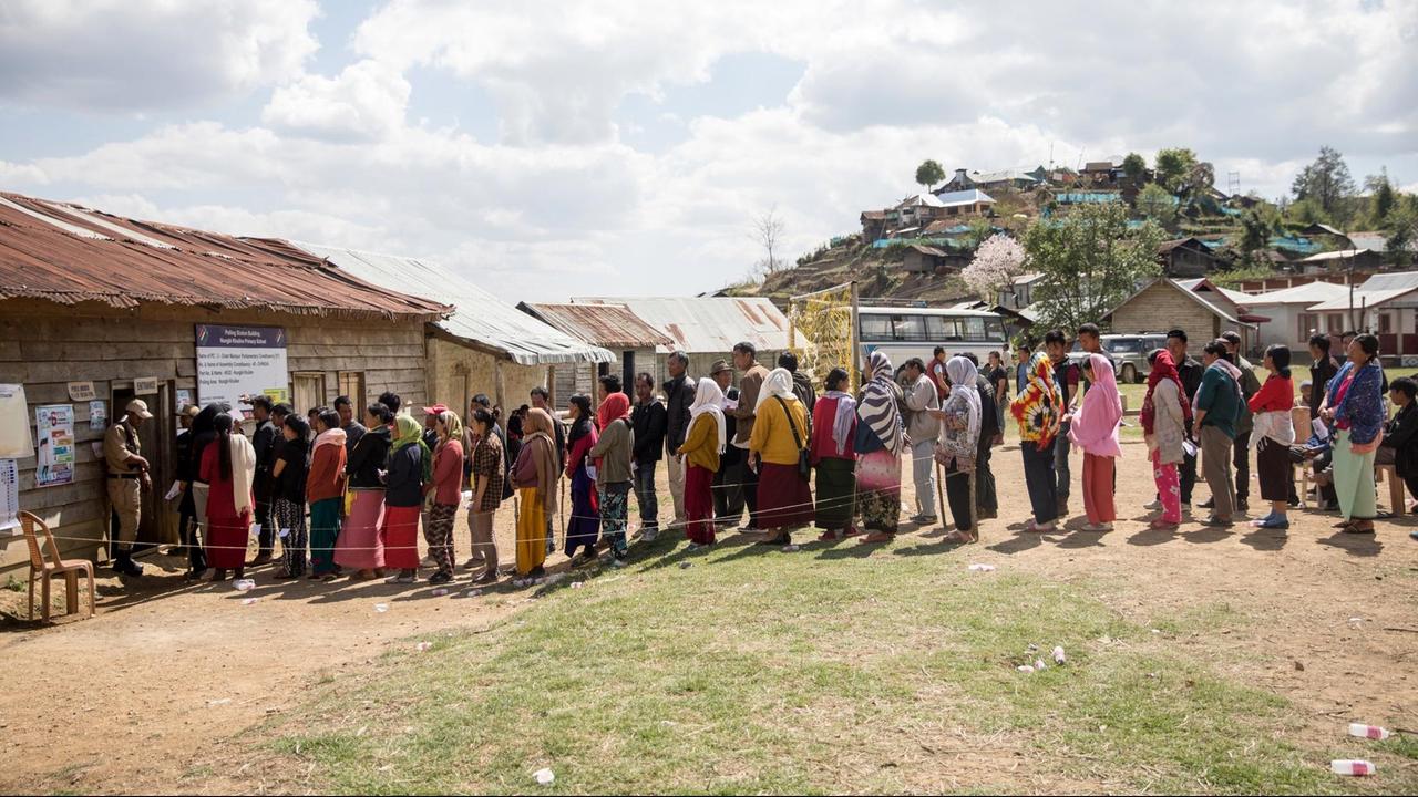 Menschen stehen vor einem Wahllokal im indischen Bundesstaat Manipur Schlange.
