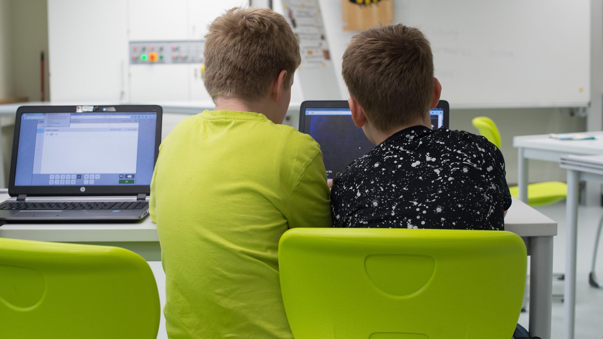 Zwei Schüler sitzen in einer Grundschule in Dresden an einem Laptop.