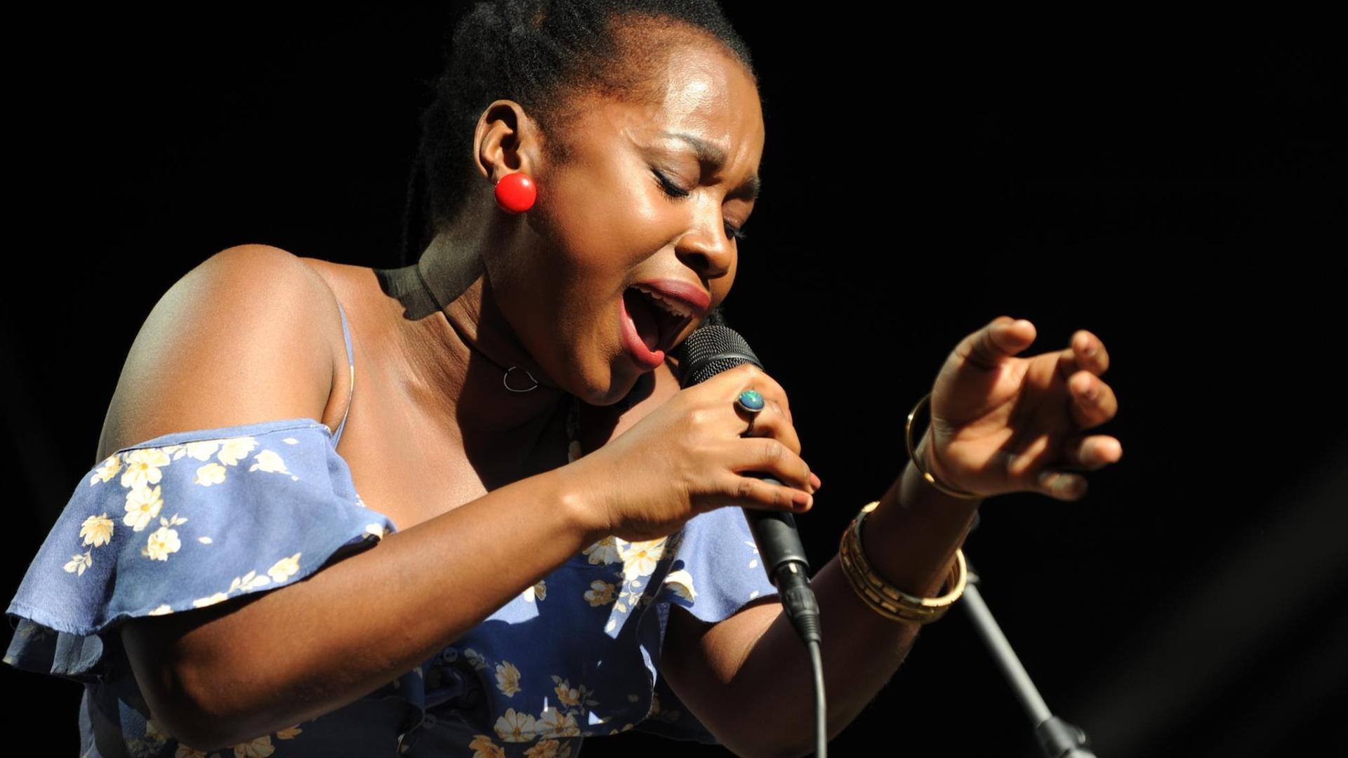 Eine Frau singt auf einer Bühne in ein Mikrofon.