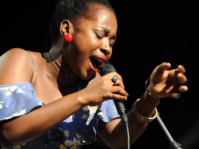 Eine Frau singt auf einer Bühne in ein Mikrofon.