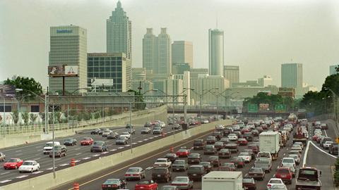 Auf einem Highway durch die Innenstadt von Atlanta stauen sich Autos auf den sieben Fahrspuren. Der Blick auf die Skyline der Südstaaten-Metropole ist von den Abgasen verhangen.