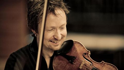 Der Geiger Daniel Sepec mit erhobenem Bogen und Geige auf der Schulter