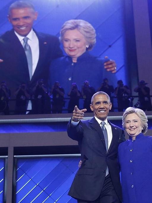 Präsident Barack Obama und Präsidentschaftsbewerberin Hillary Clinton umarmen sich auf dem Parteitag der US-Demokraten und winken den Delegierten zu