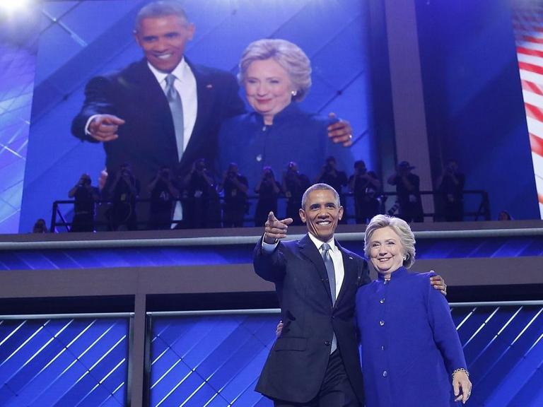 Präsident Barack Obama und Präsidentschaftsbewerberin Hillary Clinton umarmen sich auf dem Parteitag der US-Demokraten und winken den Delegierten zu