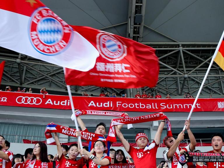 Chinesische Fans des FC Bayern München in Shanghai mit Bayern- und Deutschlandfahnen