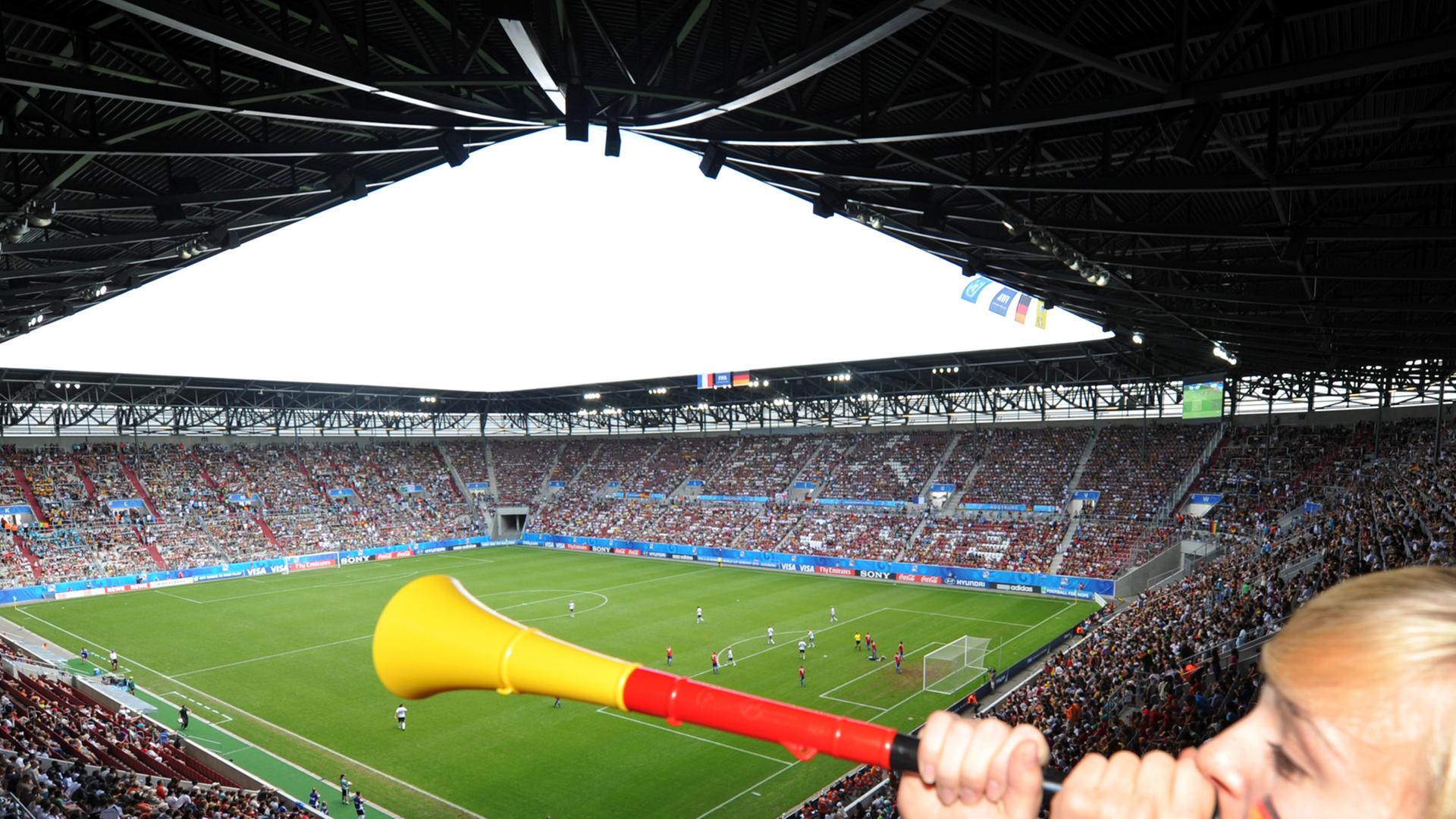 Eine Zuschauerin bläst in einem Stadion in eine Vuvuzela.