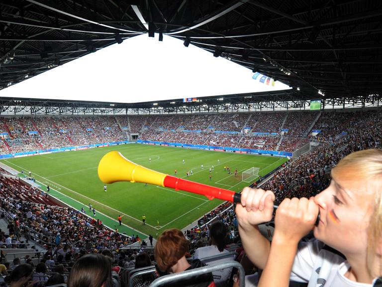 Eine Zuschauerin bläst in einem Stadion in eine Vuvuzela.