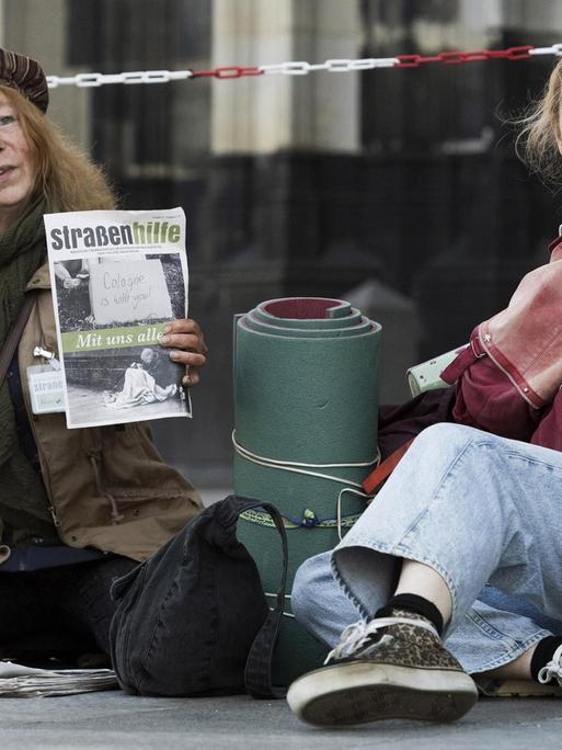 Szene aus dem Kölner "Tatort" mit dem Titel "Wie alle anderen auch" vom 21.03.2021: Ella Jung (Ricarda Seifried, r.) sitzt neben einer Frau (Rike Eckermann, l.), die am Dom Obdachlosenzeitungen verkauft.