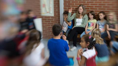 Die Lehrerin Lena Hornbostel sitzt mit Schülern im Kreis.