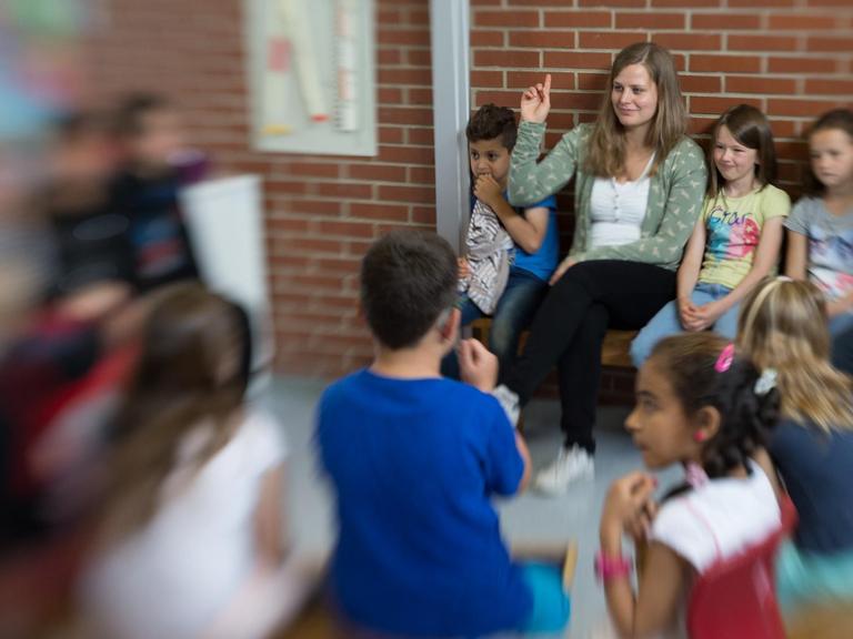 Die Lehrerin Lena Hornbostel sitzt mit Schülern im Kreis.