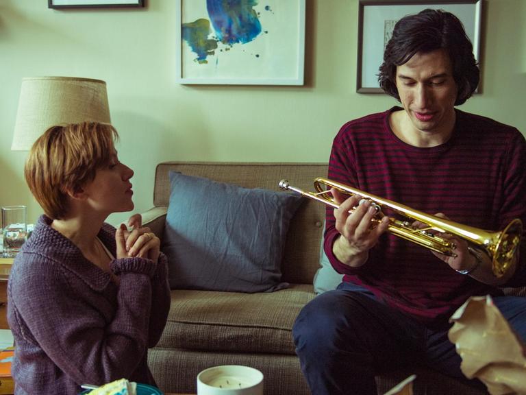 Szene aus dem Film "Marriage Story": Nicole (Scarlett Johansson) und Charlie (Adam Driver) zusammen im Wohnzimmer, er hat eine Trompete in der Hand.