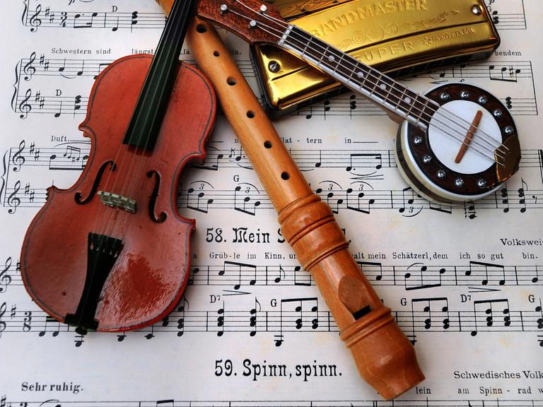 Eine Geige, eine Flöte, eine Mundharmonika und ein Banjo liegen auf einem Notenblatt.