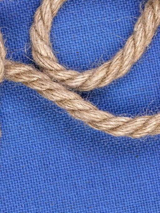 Ein geknotetes Seil vor blauem Hintergrund.