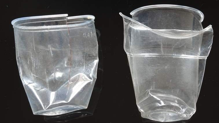 Zwei zerdrückte Plastikbecher liegen nebeneinander