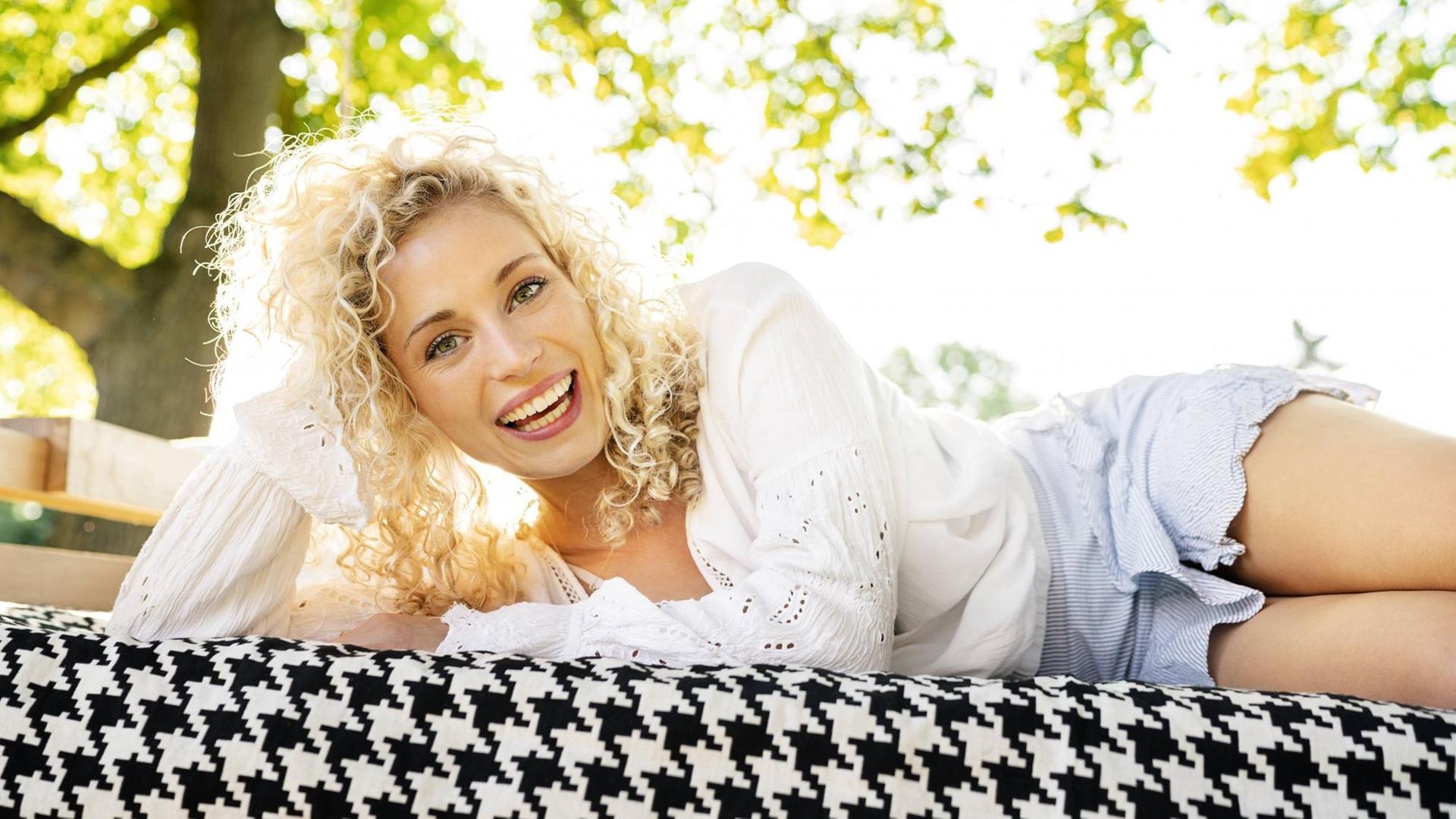 Happy young woman lying on a bed in garden model released Symbolfoto property released