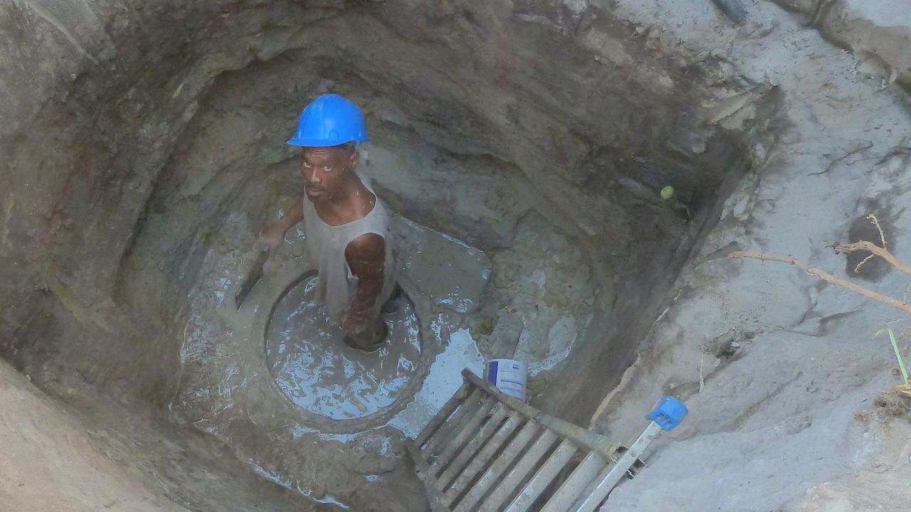 Arbeiter in einem tiefen Brunnen mit Schaufel