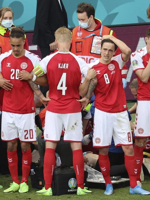 EM-Spiel Dänemark gegen Finnland: Die Mitspieler von Christian Eriksen schirmen ihren Kapitän vor den Kameras und den neugierigen Blicken ab.