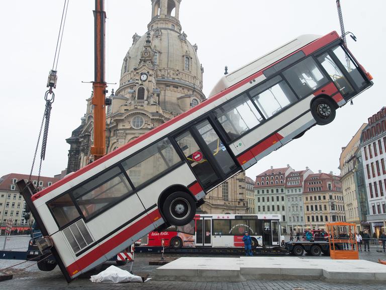 Ein Linienbus wird am 06.02.2017 auf dem Neumarkt vor der Frauenkirche in Dresden von einem Kran in eine senkrechte Position gehoben.