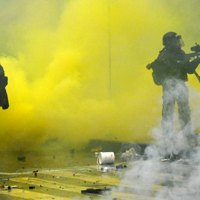 Das Foto zeigt bewaffnete Polizisten in gelbem Rauch bei einem Einsatz auf einer Kundgebung gegen Präsdient Duque in Bogotá/Kolumbien.