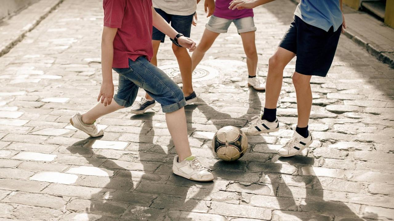 Kinder und Jugendliche spielen Fußball auf der Straße
