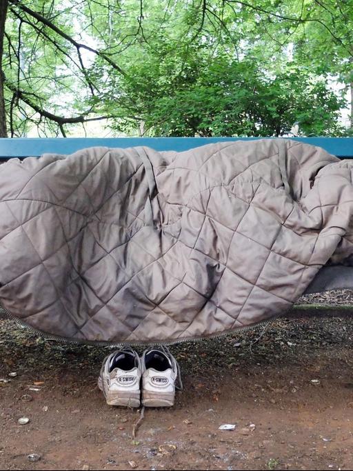 Ein Obdachloser schläft auf einer Bank in einem Park in Düsseldorf.