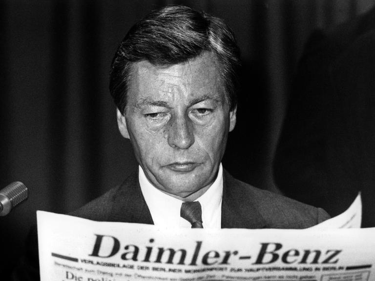 Der Vorstandssprecher der Deutschen Bank Alfred Herrhausen liest eine Firmenzeitung zu Beginn der Hauptversammlung der Daimler Benz AG am 28.06.1989 in Berlin.