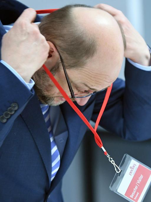 Der SPD-Kanzlerkandidat Martin Schulz hängt sich im Unternehmen "Pedag International" in Königs Wusterhausen in Brandenburg ein Besucherschild um.
