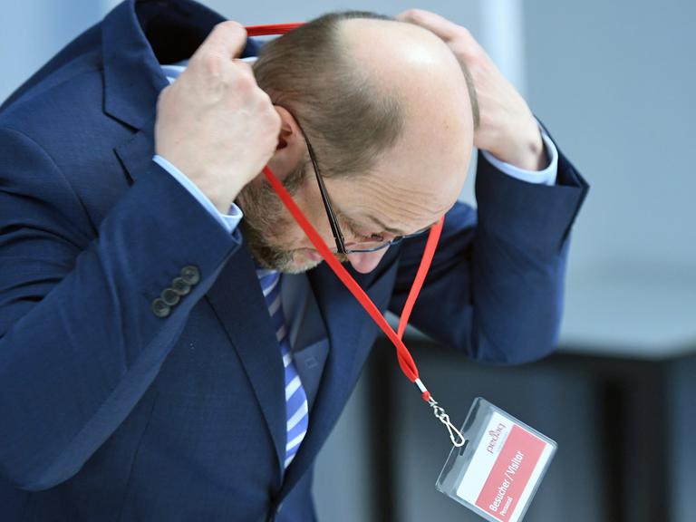 Der SPD-Kanzlerkandidat Martin Schulz hängt sich im Unternehmen "Pedag International" in Königs Wusterhausen in Brandenburg ein Besucherschild um.