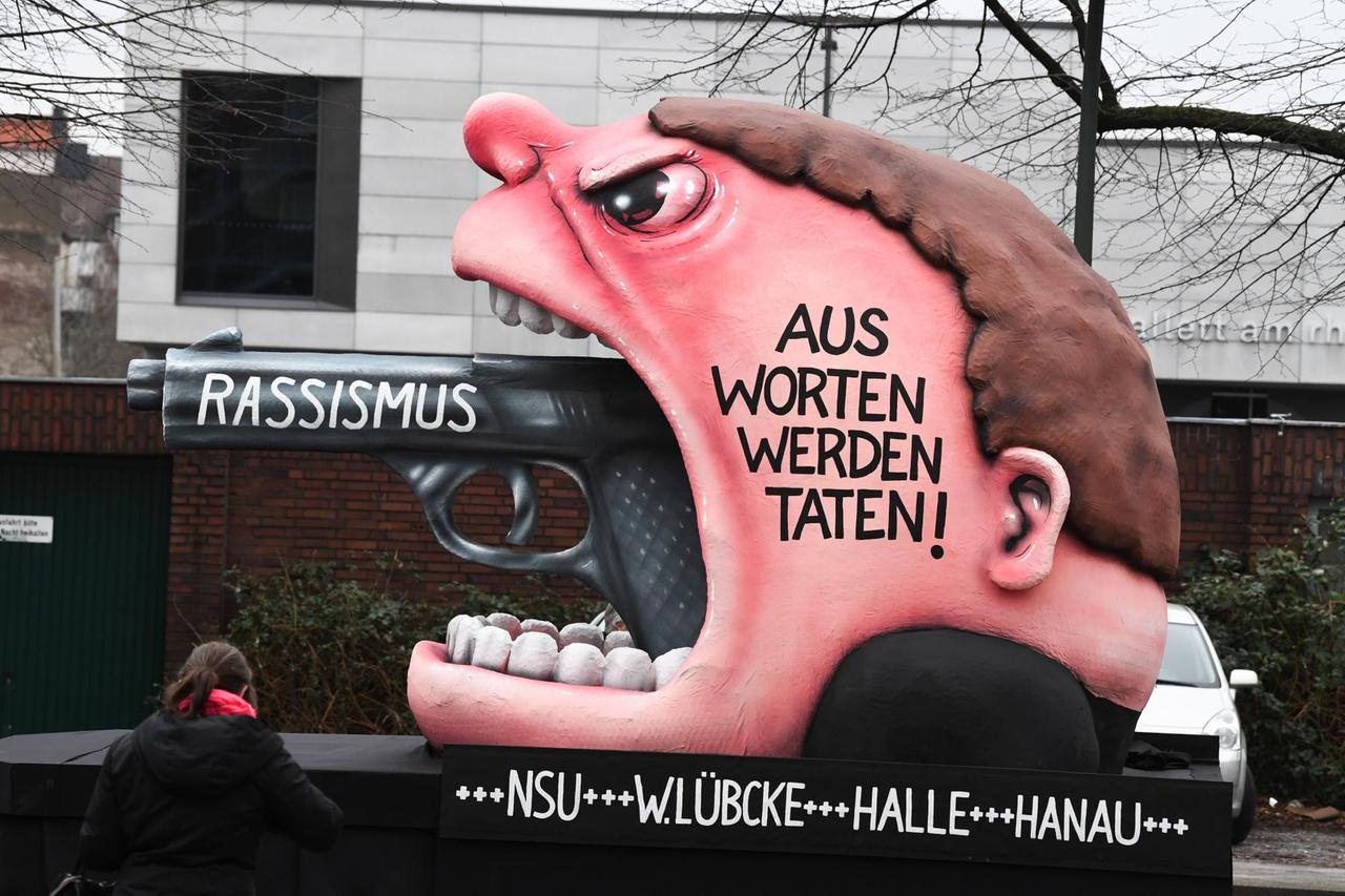 Ein Motivwagen "Rassismus - Aus Worten werden Taten! +++ NSU +++ W. Lübcke +++ Halle +++ Hanau" steht vor dem Rosenmontagszug auf der Straße. Ein Motivwagen "Rassismus - Aus Worten werden Taten! +++ NSU +++ W. Lübcke +++ Halle +++ Hanau" steht vor dem Rosenmontagszug auf der Straße.