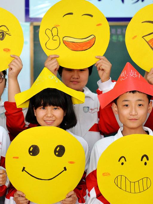 Schüler im chinesischen Xingtai zeigen ihre gemalten Smileys.