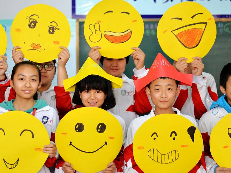 Schüler im chinesischen Xingtai zeigen ihre gemalten Smileys.