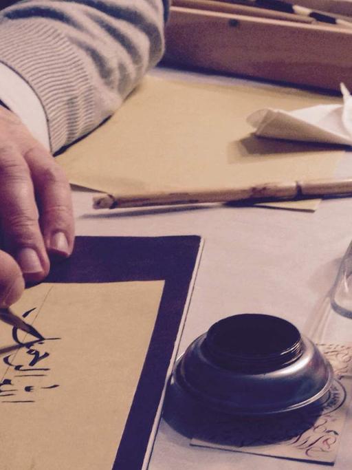 Ein Kalligraph vertieft sich in einen Vers des Korans.