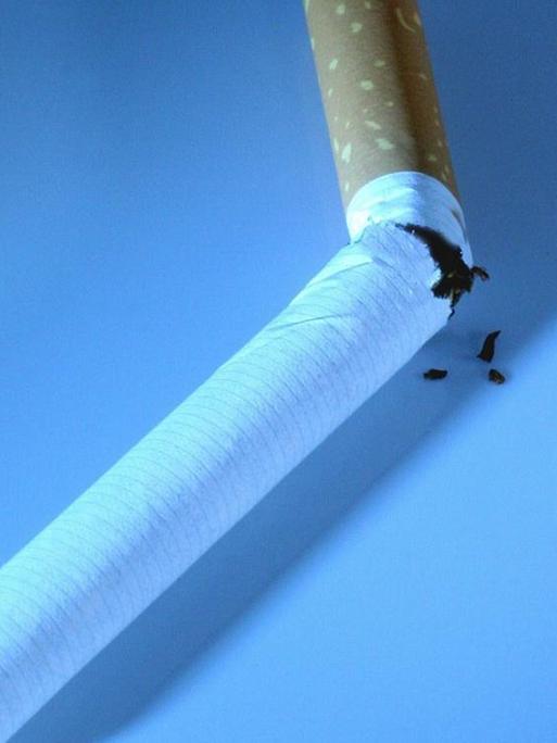 Eine zerbrochene Zigarette vor blauem Hintergrund.