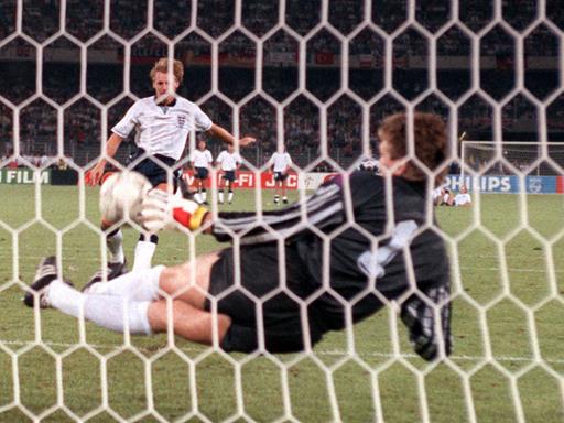 Torhüter Bodo Illgner (vorn) pariert den vom englischen Abwehrspieler Stuart Pearce getretenen Elfmeter. Damit ist die deutsche Fußballnationalmannschaft beim Stand von 3:3 im Elfmeterschießen mit England im Vorteil. Sie gewinnt am 04.07.1990 im Turiner Stadion delle Alpi das Halbfinalspiel der Fußball-WM am Ende mit 4:3. Nach der Verlängerung hatte es 1:1 gestanden.