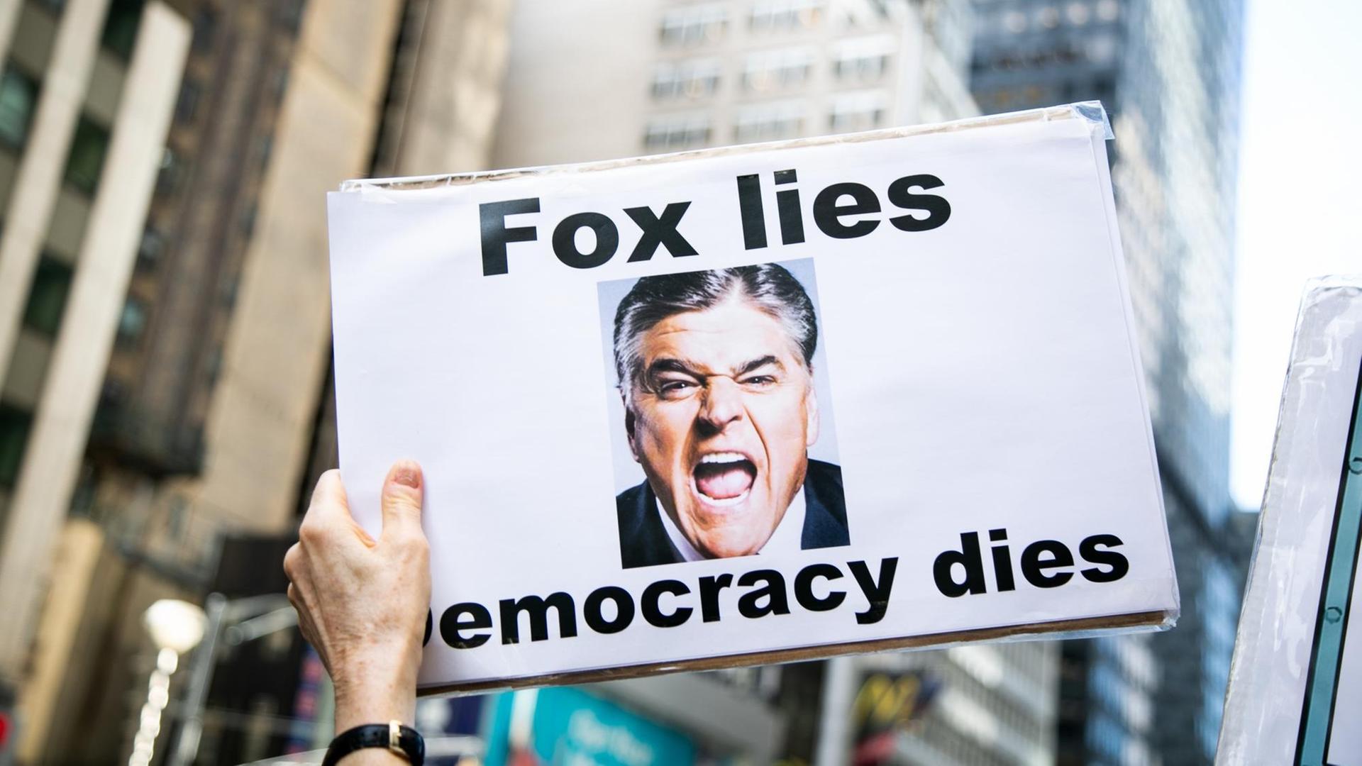 Eine Demonstrantin hält ein Schild mit der Aufrschrift "Fox lies, democracy dies".